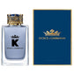 A sleek, masculine glass perfume bottle containing Dolce & Gabbana K Eau de Toilette. The bottle features a bold, modern design with a dark blue hue, suggesting a sophisticated and masculine fragrance